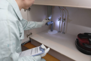 Image of man in work clothes checking under the sink stock performing inspection